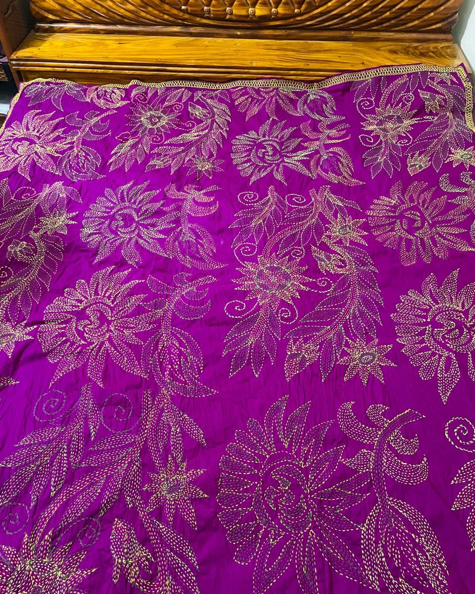 The purple kantha's braided gold edge and sunflower motifs