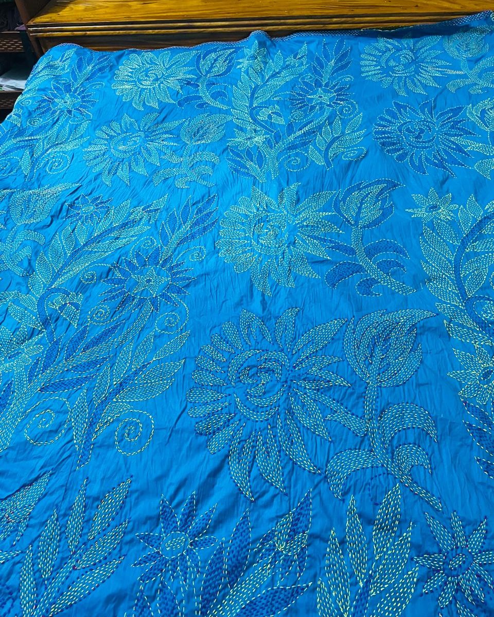 Close view of the turquoise kantha's sunflower and leaf stitching